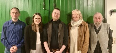 Zwei Frauen und drei Männer stehen vor einer grünen Tür