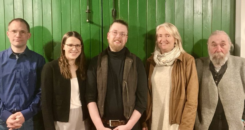 Zwei Frauen und drei Männer stehen vor einer grünen Tür